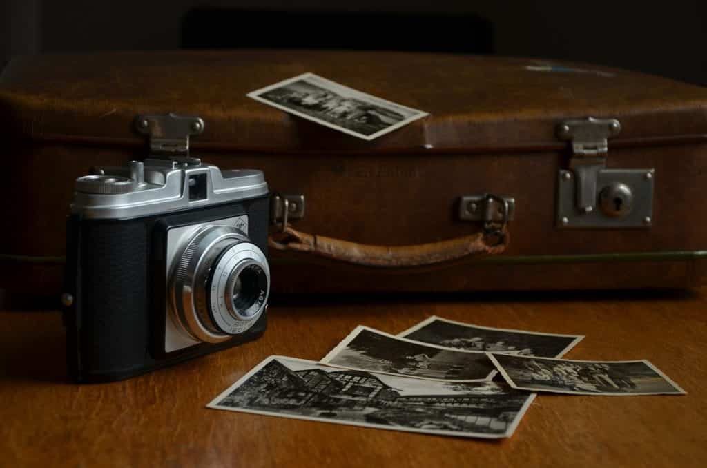 Vintage suitcase in the background; polaroid camera in the front left corner.