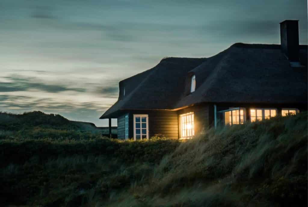 Gray house surrounded by grass under a blue, cloudy night sky.